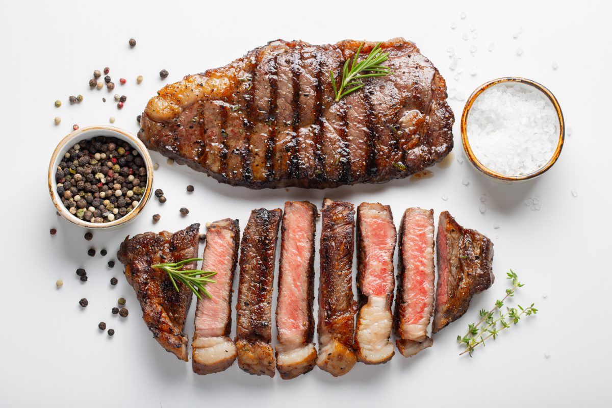 Two grilled marbled beef steaks striploin with spices isolated on white background, top view